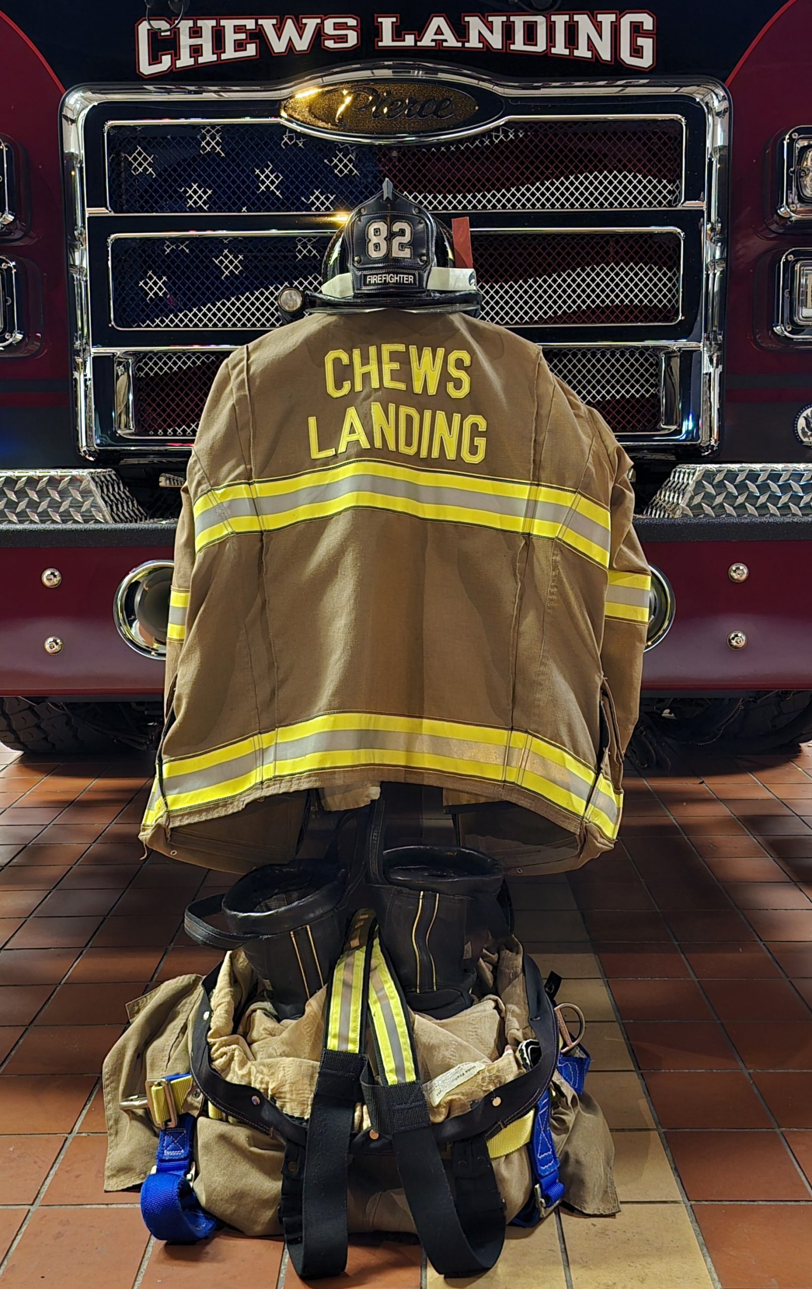 Firefighter's gear arranged in front of a fire truck with "chews landing" prominently displayed on the back of the jacket.